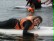Eine Schülerin liegt auf dem Surfbrett und paddelt mit den Armen